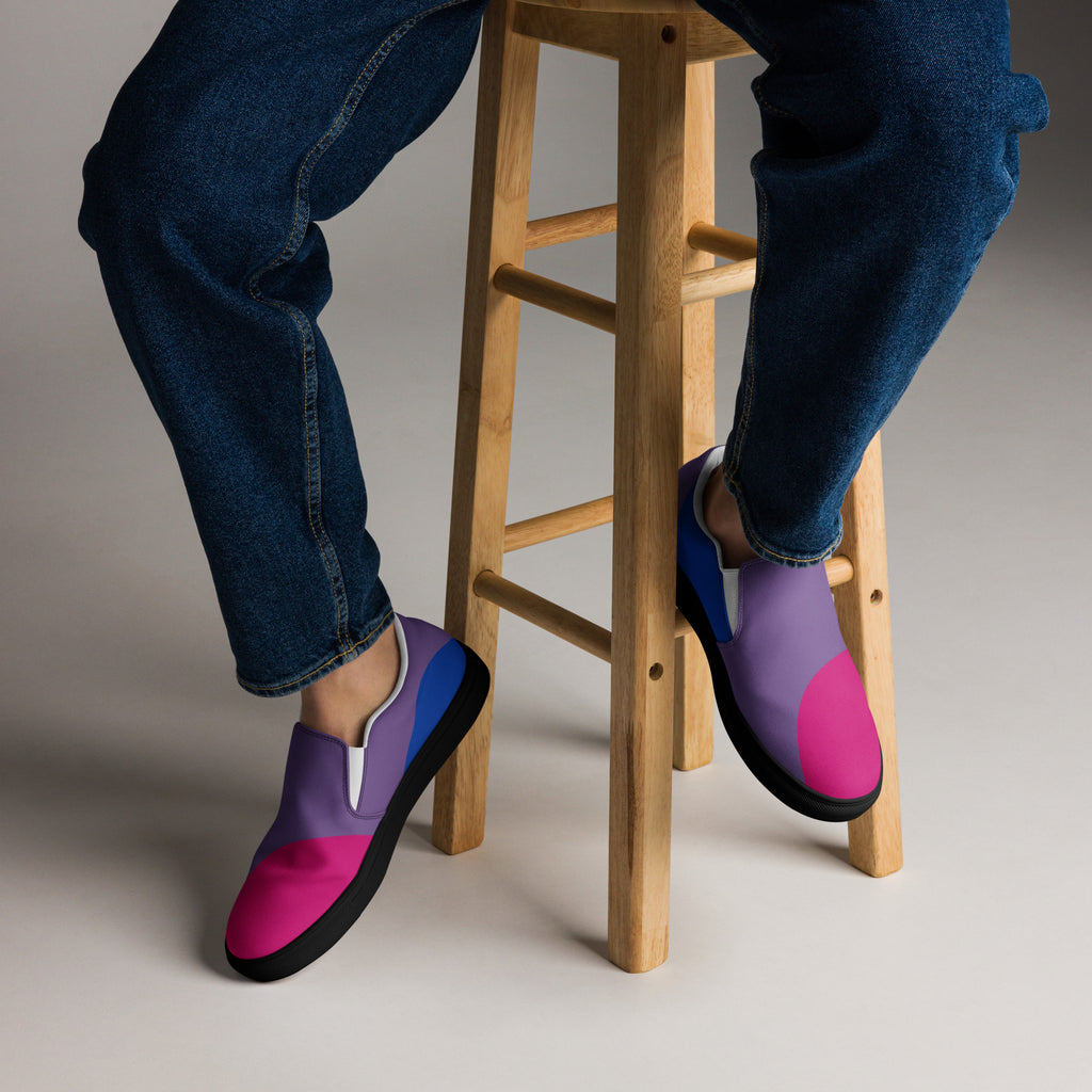 Purple and pink shoes worn with blue jeans on a wooden stool.