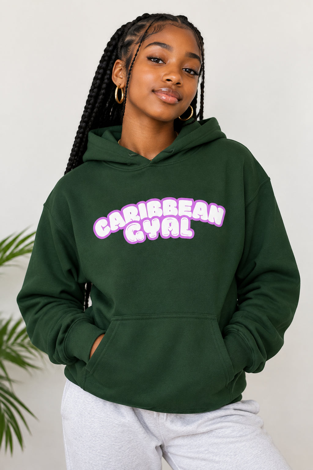 A dark forest green pullover hoodie with a front graphic print that reads 'Caribbean Gyal'