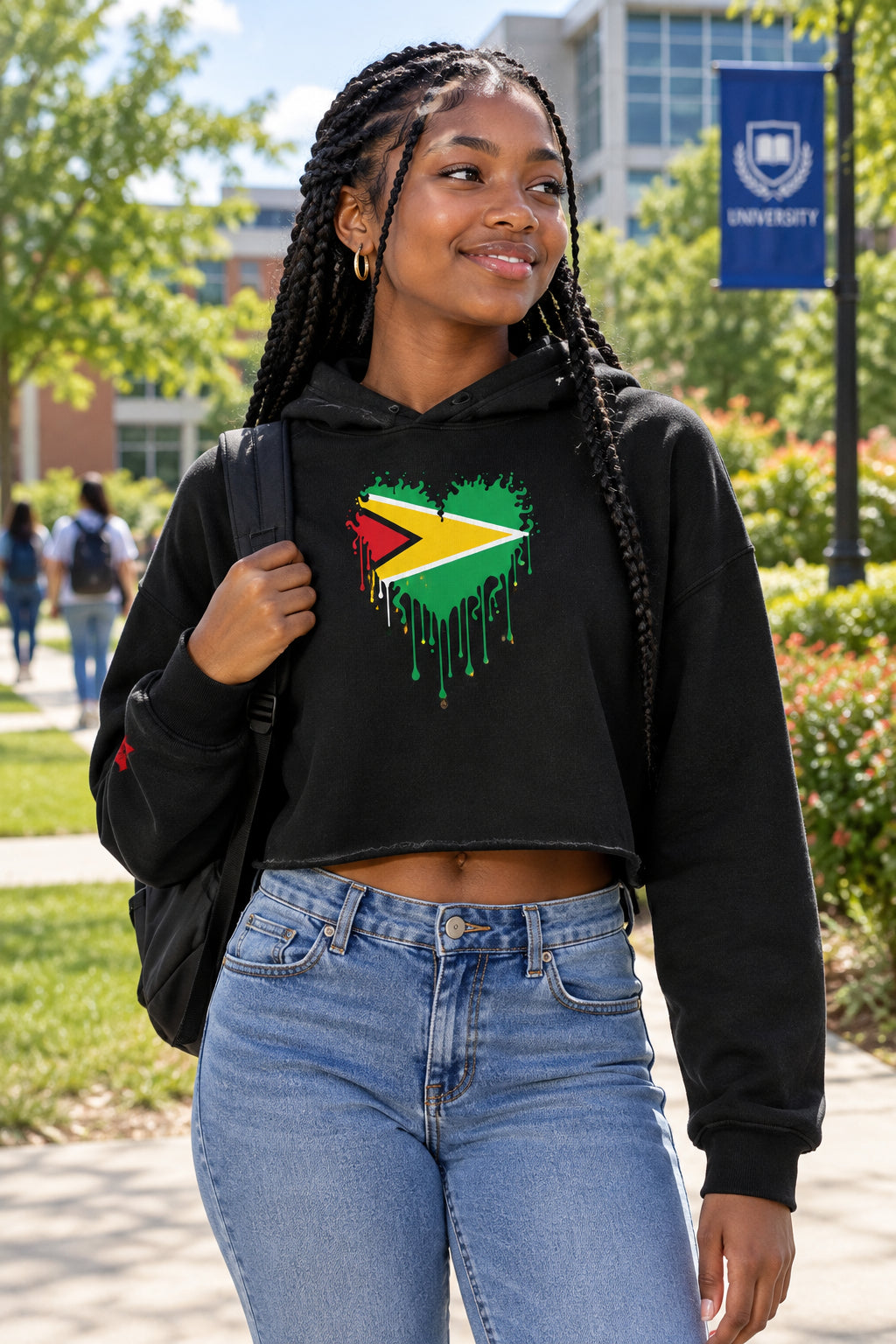 A black cropped hoodie with a graphic of the Guyana flag forming a heart shape on the chest, with a dripping paint effect. The hoodie is shown against a plain white background.