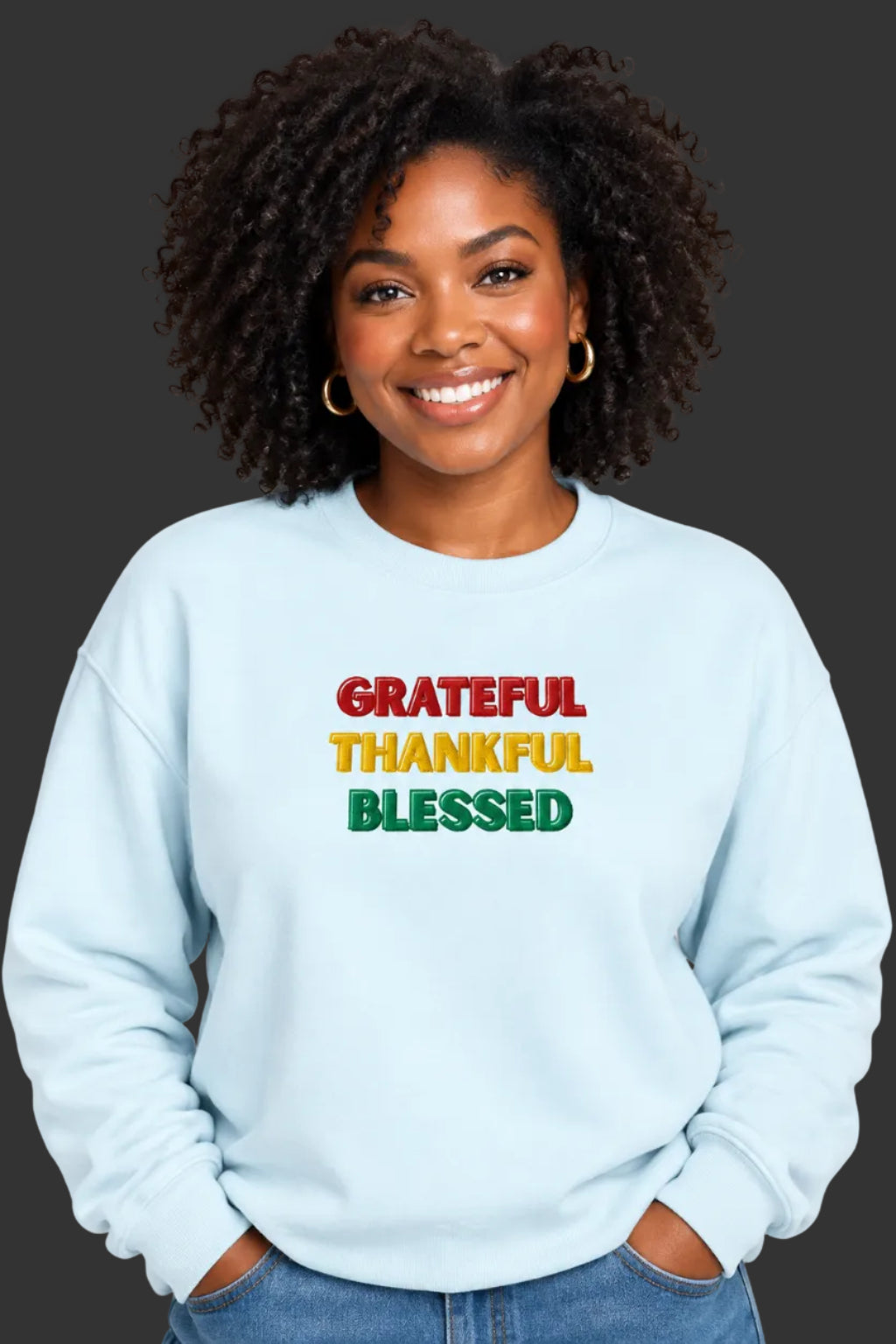 A light blue crewneck sweatshirt with the words 'GRATEFUL THANKFUL BLESSED' printed on the chest in red, yellow, and green block letters.