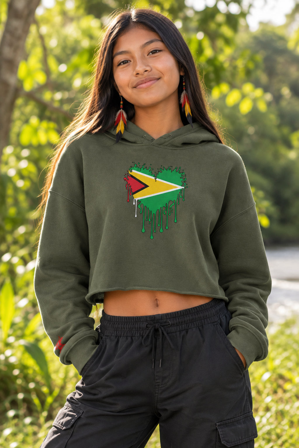 An olive green cropped hoodie sweatshirt featuring a graphic of the Guyana flag inside a dripping heart design on the chest, displayed against a solid white background.