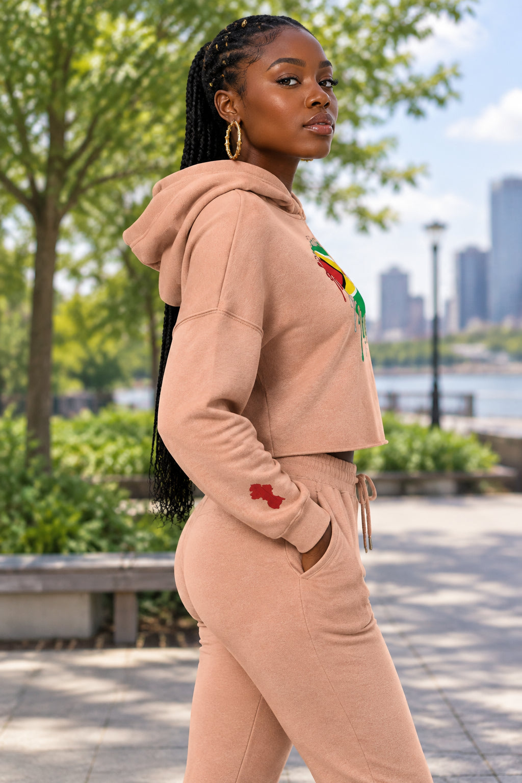 A peach cropped hoodie with a graphic of the Guyana flag forming a heart shape on the chest, with a dripping paint effect. The hoodie is shown against a plain white background.