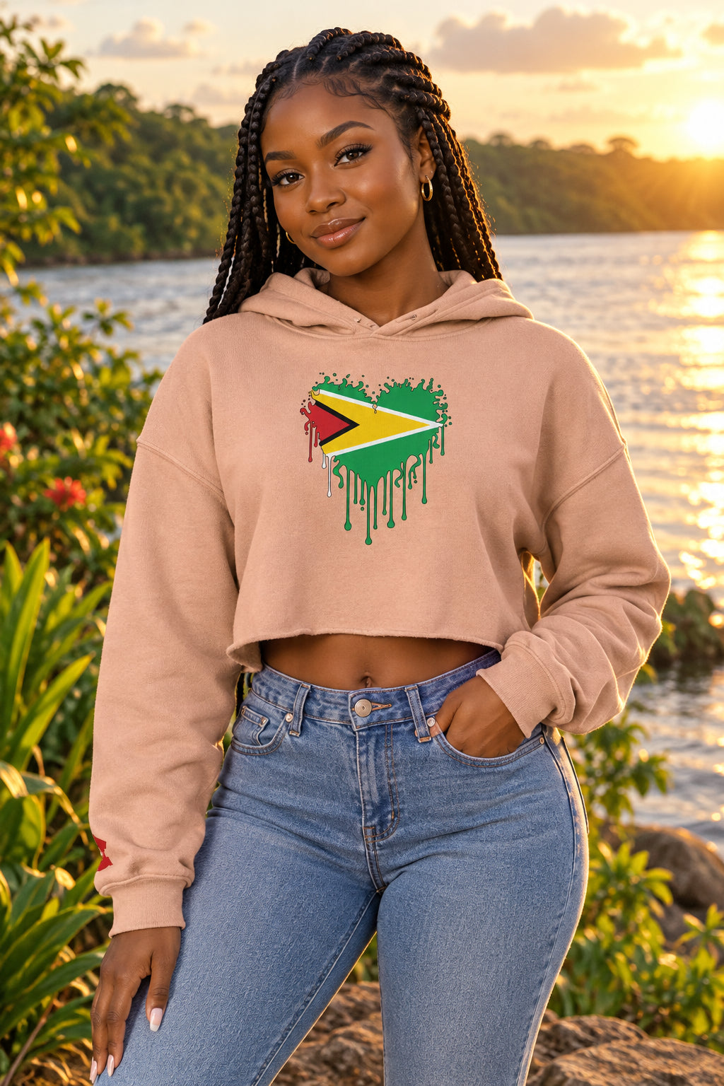 A cropped long-sleeve hoodie in a dusty peach-beige color, featuring a graphic of the Guyana flag inside a dripping paint heart on the chest.