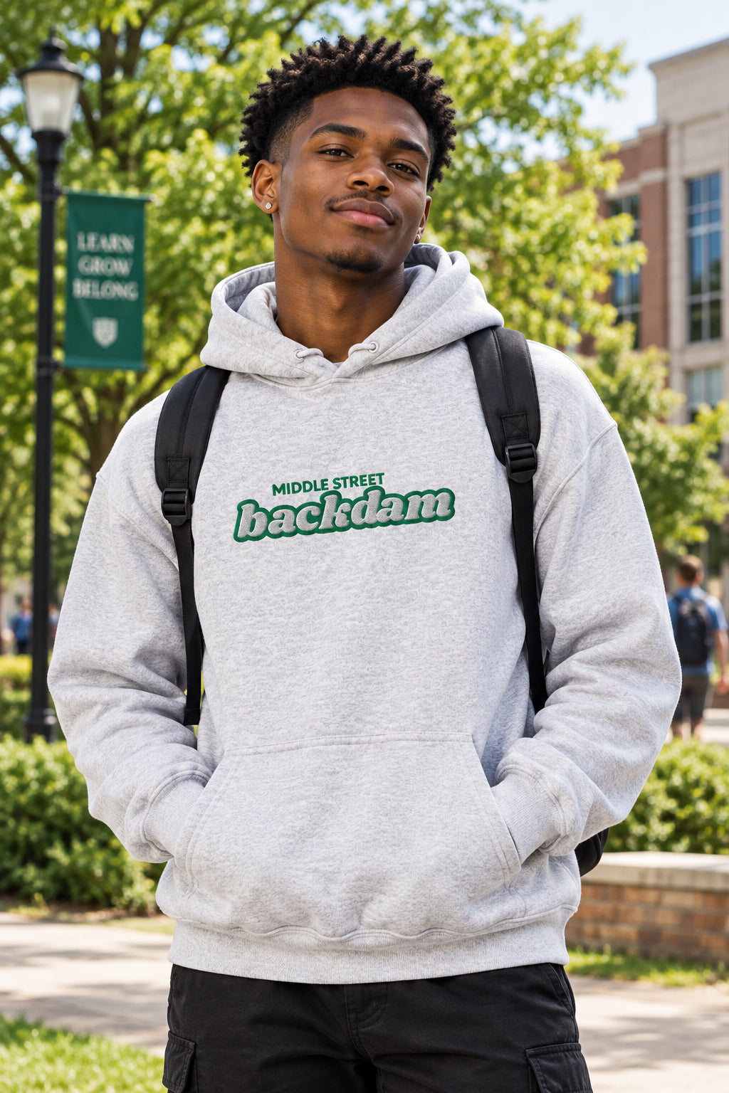 A light heather gray pullover hoodie with a green and black graphic text print reading 'MIDDLE STREET backdam' across the chest, displayed on a solid white background.