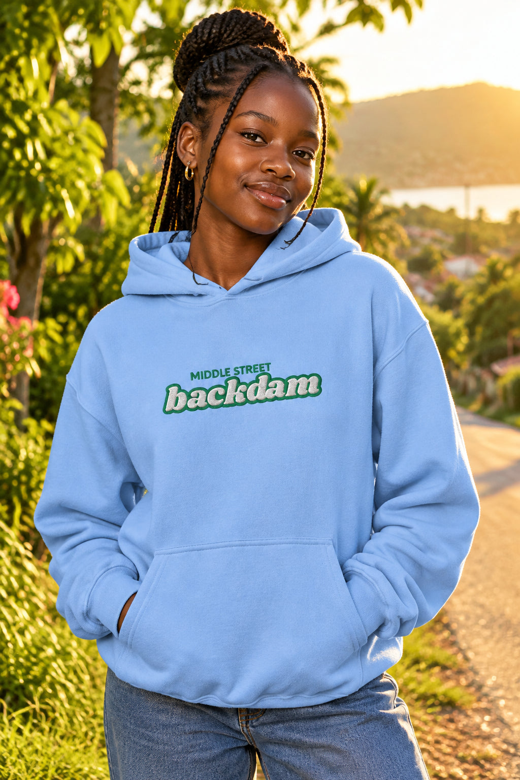 A light blue pullover hoodie with a front kangaroo pocket and a chest graphic that reads 'MIDDLE STREET backdam' in green and white. A small black graphic is visible on the left sleeve cuff.