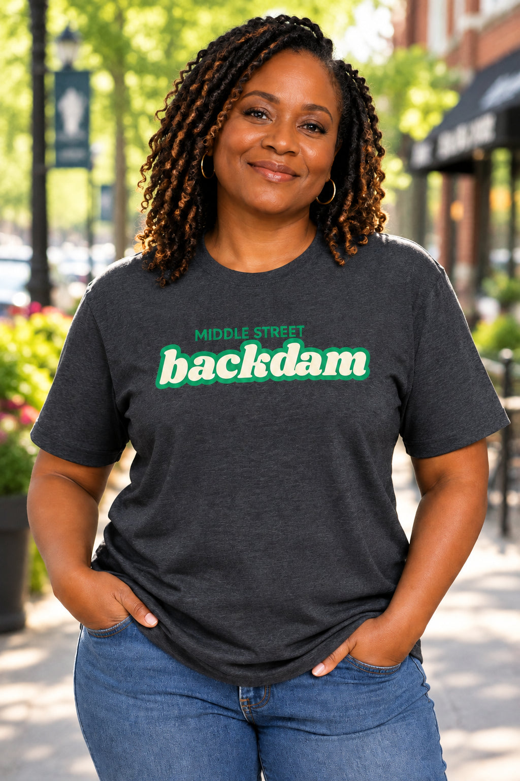 A dark grey short-sleeve crewneck t-shirt featuring a green graphic print on the chest that reads 'MIDDLE STREET backdam' in a retro font.