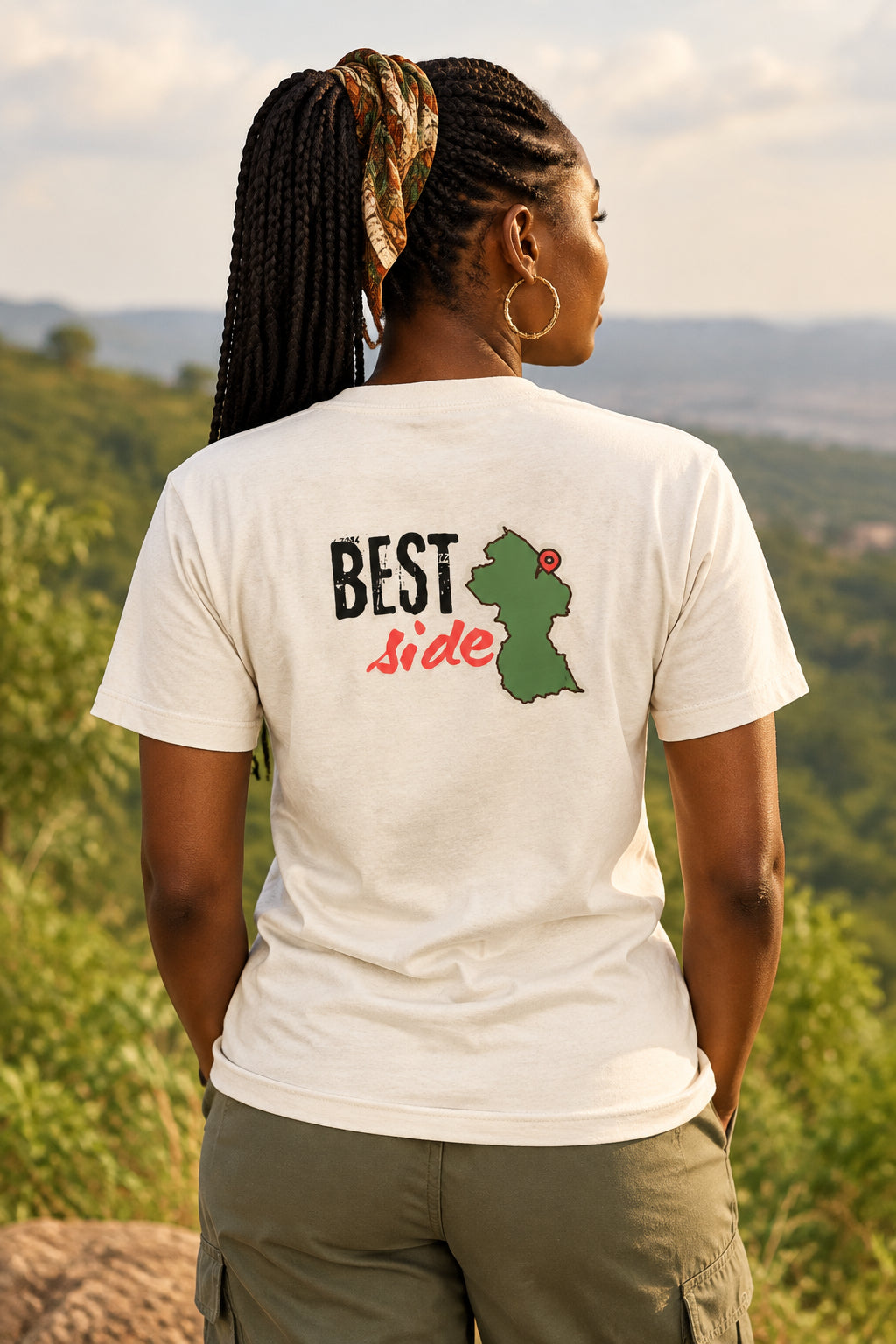 An off-white short-sleeve t-shirt shown from the back, featuring a graphic print with the text 'BEST Side' and a green Guyana map with a red pin.