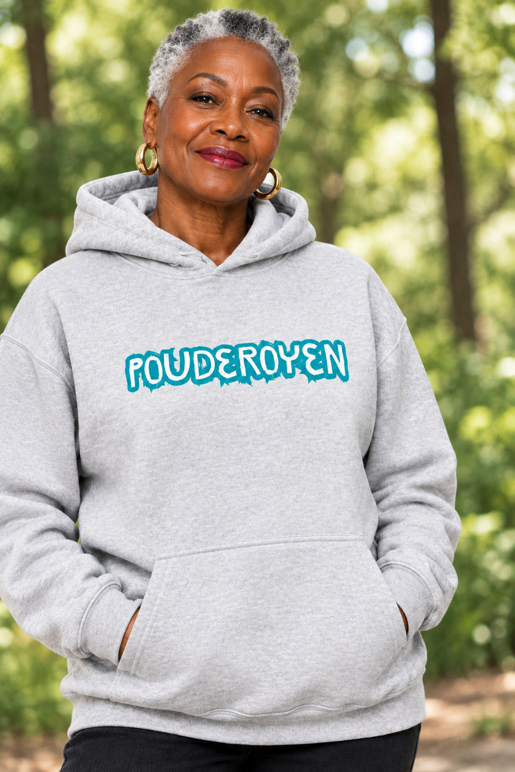 A light heather gray pullover hoodie with 'POUDEROYEN' printed across the chest in a bright blue bubbly font, featuring a kangaroo pocket and a small red embroidered map of Guyana on the left sleeve.