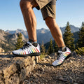 White sneakers with black laces and colorful abstract patterns on a white background