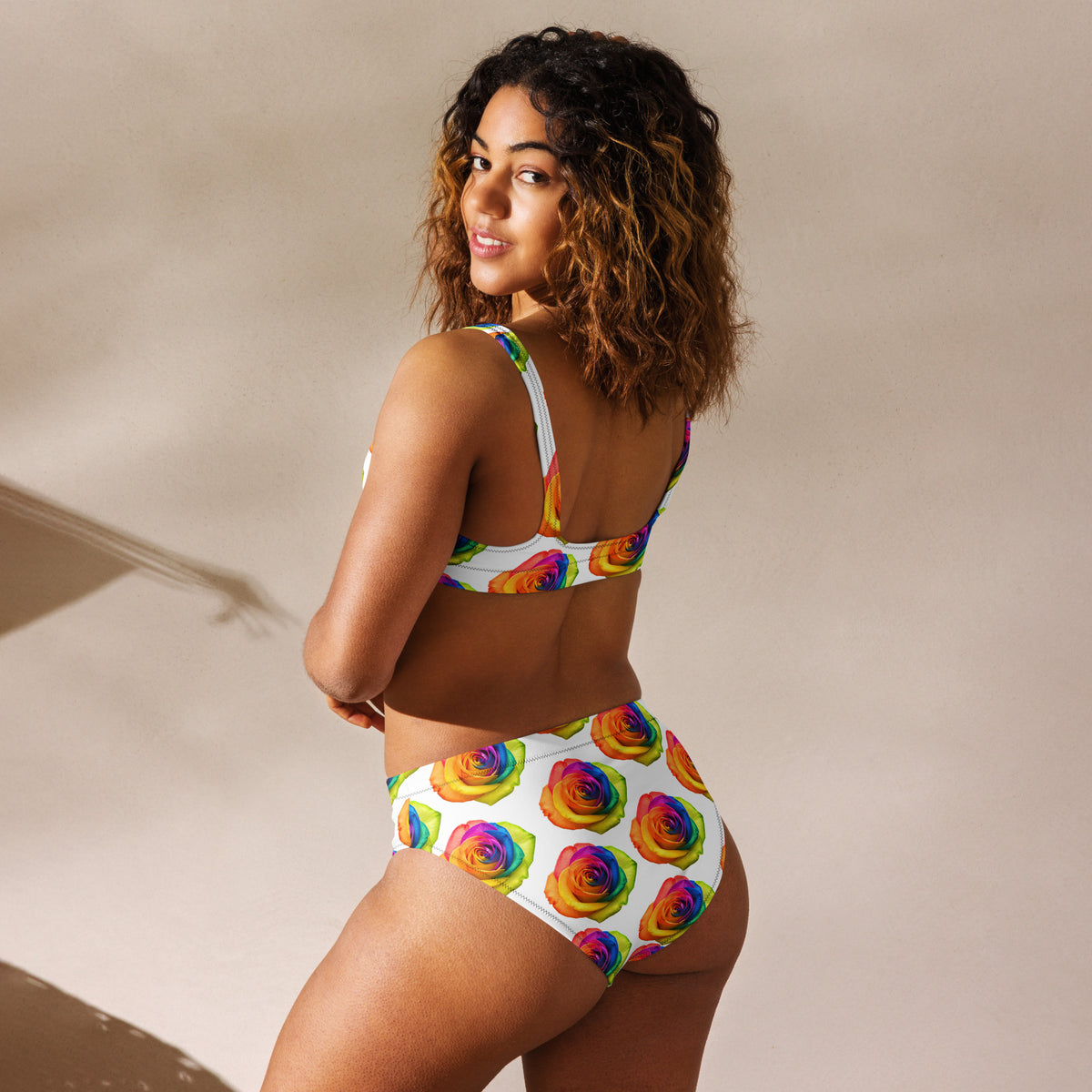 Woman wearing a colorful bikini with a rainbow flower pattern on a beige background
