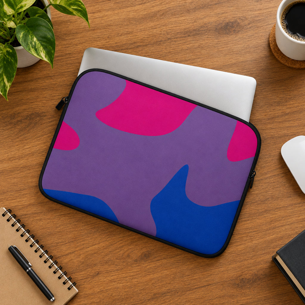 Purple and pink camouflage laptop sleeve on a light gray surface with green leaves.